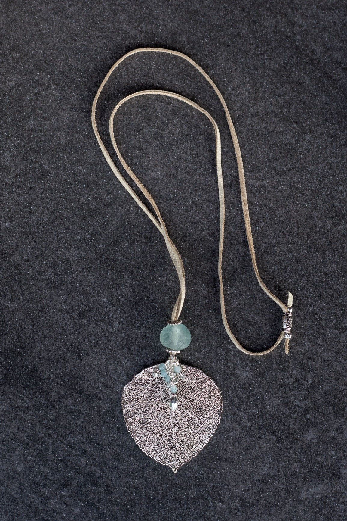 Single re-cycled African glass bead with a large silver Aspen leaf finished with a stunning crystal dangle . Deerskin leather