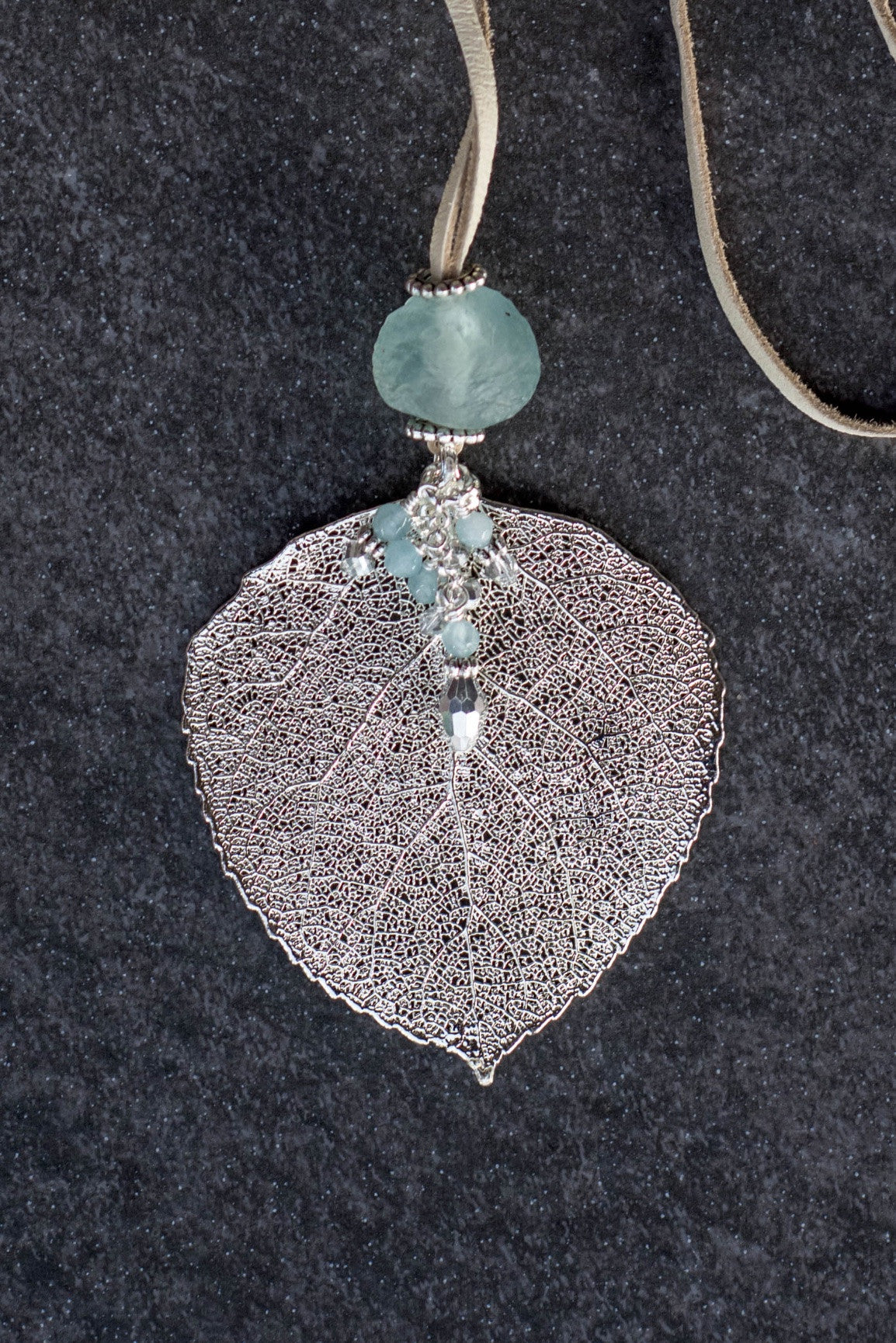 Single re-cycled African glass bead with a large silver Aspen leaf finished with a stunning crystal dangle . Deerskin leather