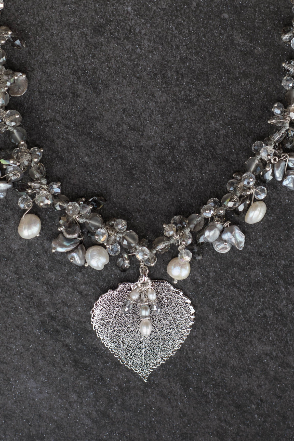 Elegant silver and white pearls are woven into this exquisite necklace with crystals and a silver Aspen leaf. A pearl & Chrystal dangle completes the piece