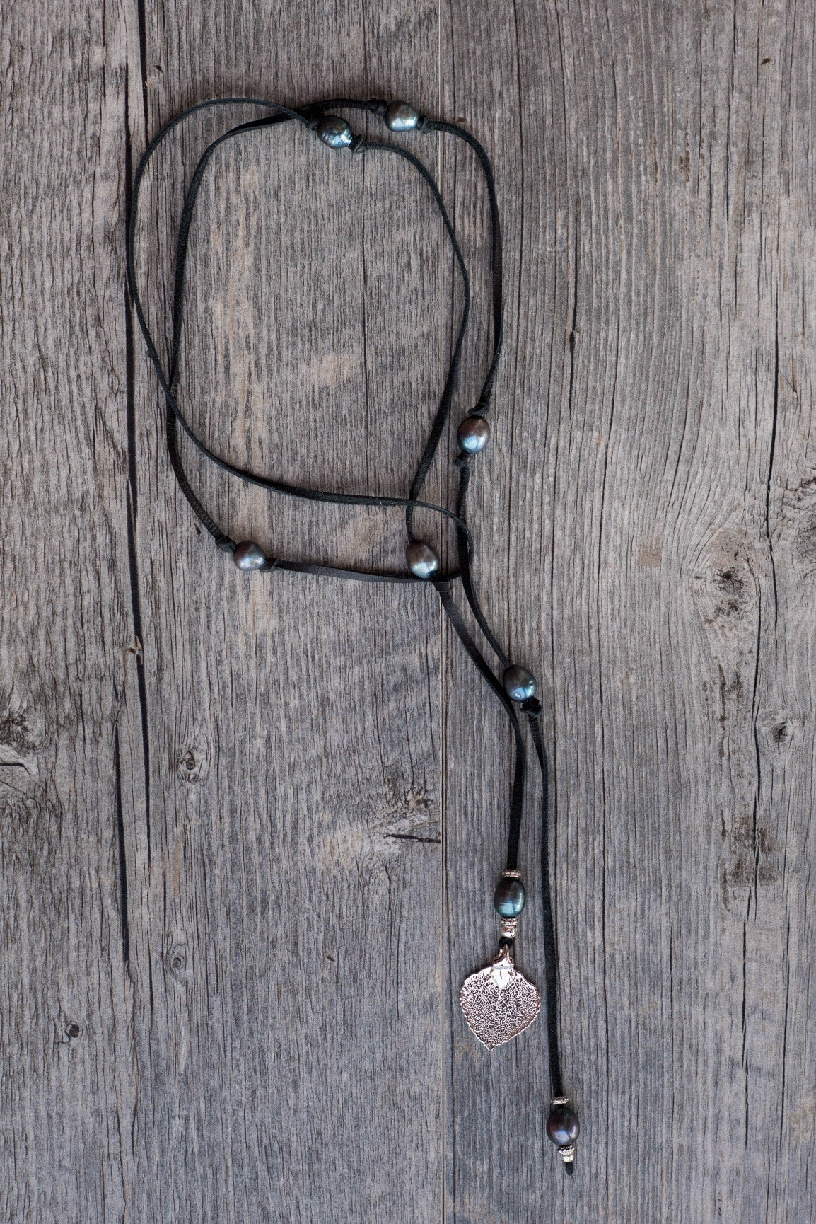 Lariat: Eight pearls highlight this versatile necklace, Peacock freshwater pearls, silver Aspen leaf, black deerskin leather.