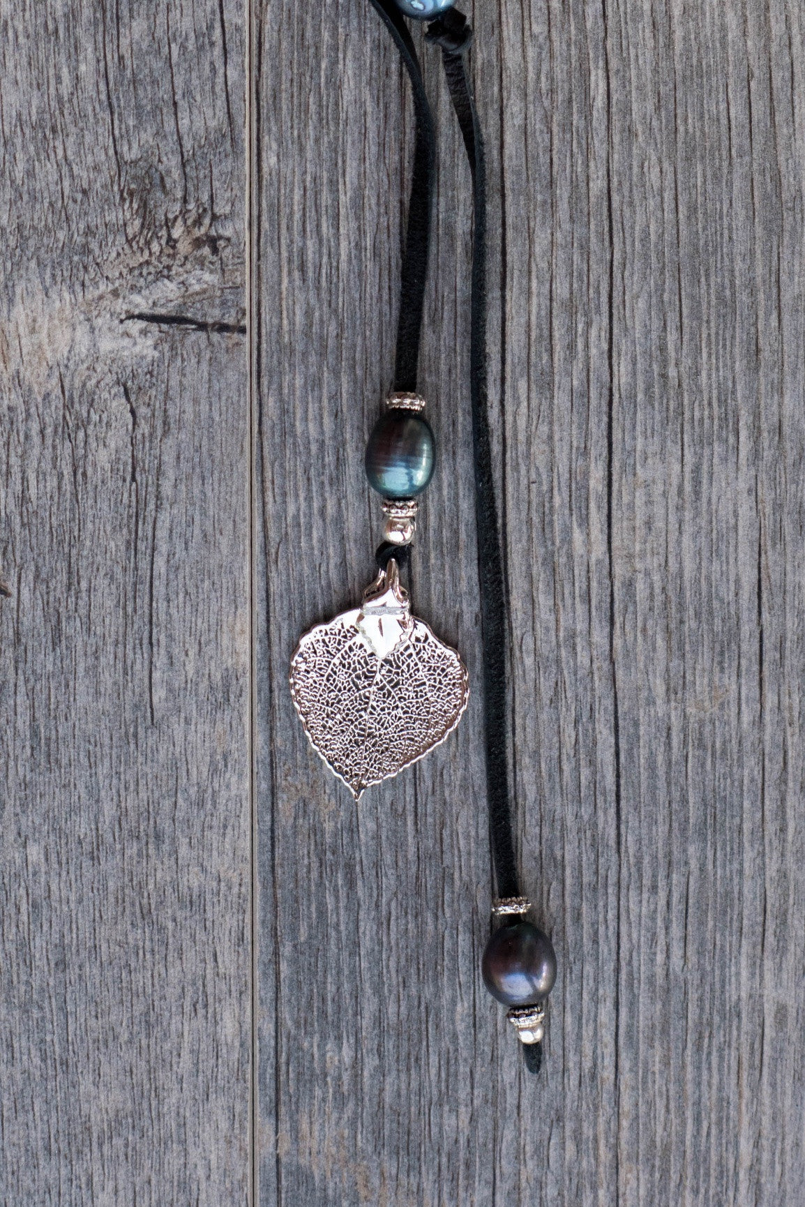 Lariat: Eight pearls highlight this versatile necklace, Peacock freshwater pearls, silver Aspen leaf, black deerskin leather.