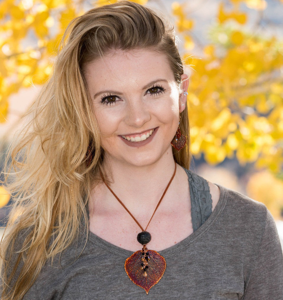 Single re-cycled African glass bead with a large Gold Aspen leaf finished with a stunning crystal dangle. Deerskin leather