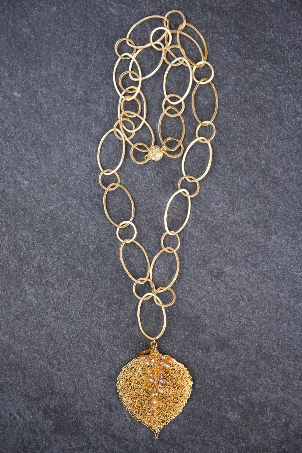 Signature gold chain combined with a large gold leaf and crystal dangles creates this striking necklace