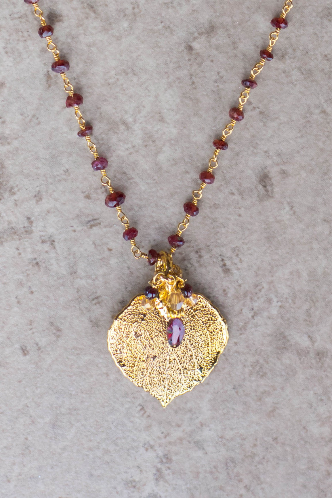 Gems in gold chain: Garnets accent the classic princess style necklace with a gold leaf