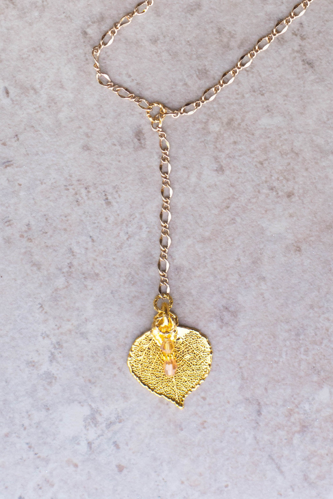 Classic Gold chain creates this dramatic Y style long necklace with a small Gold leaf