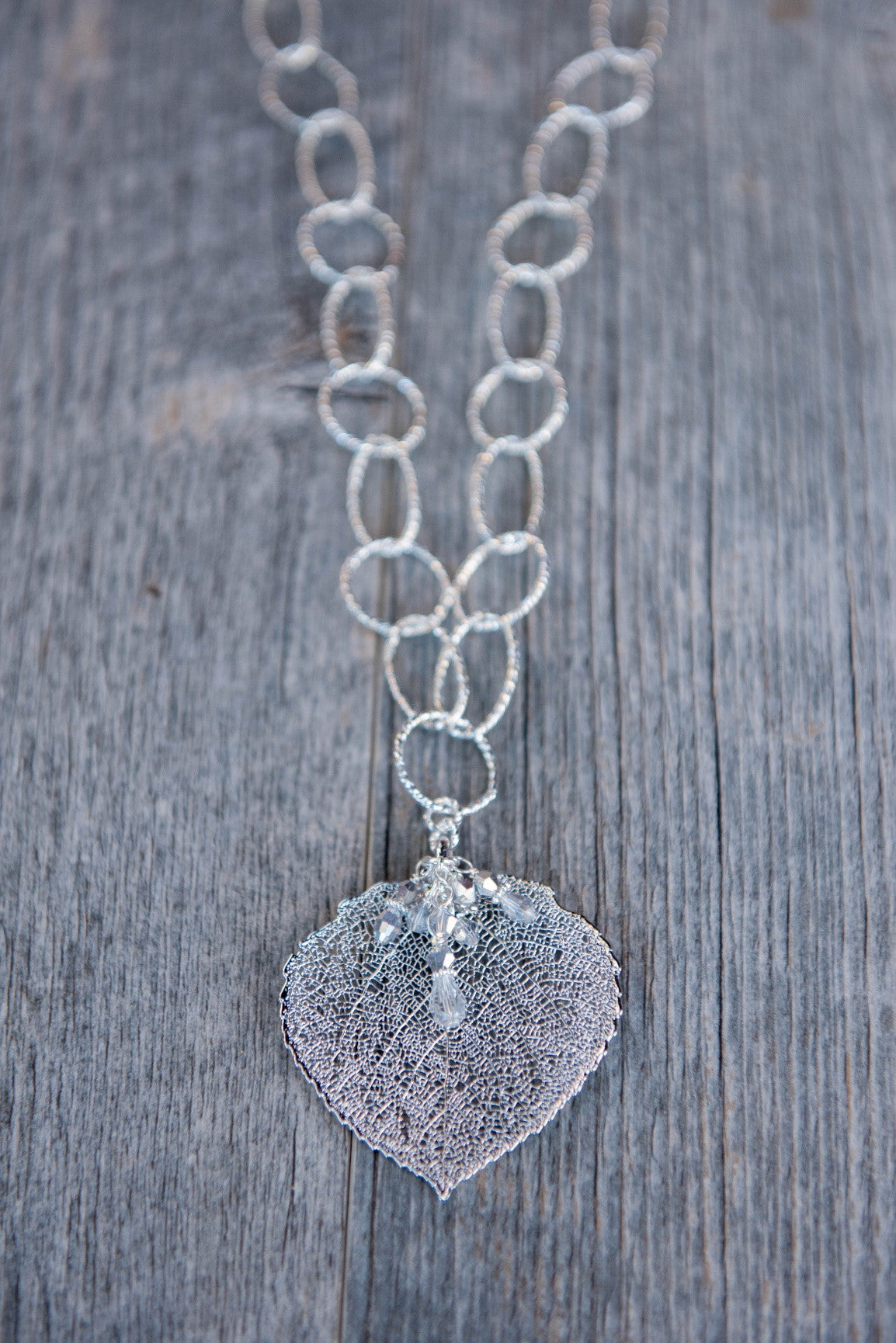 Classic silver faceted chain creates a modern long necklace with a Silver leaf and crystal dangles