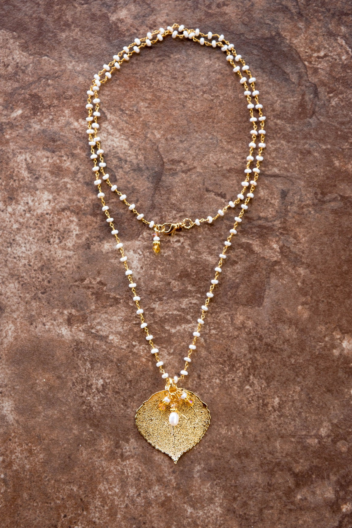 Pearls in silver chain: White freshwater pearls accent this glamorous necklace with a gold leaf and white pearls dangles