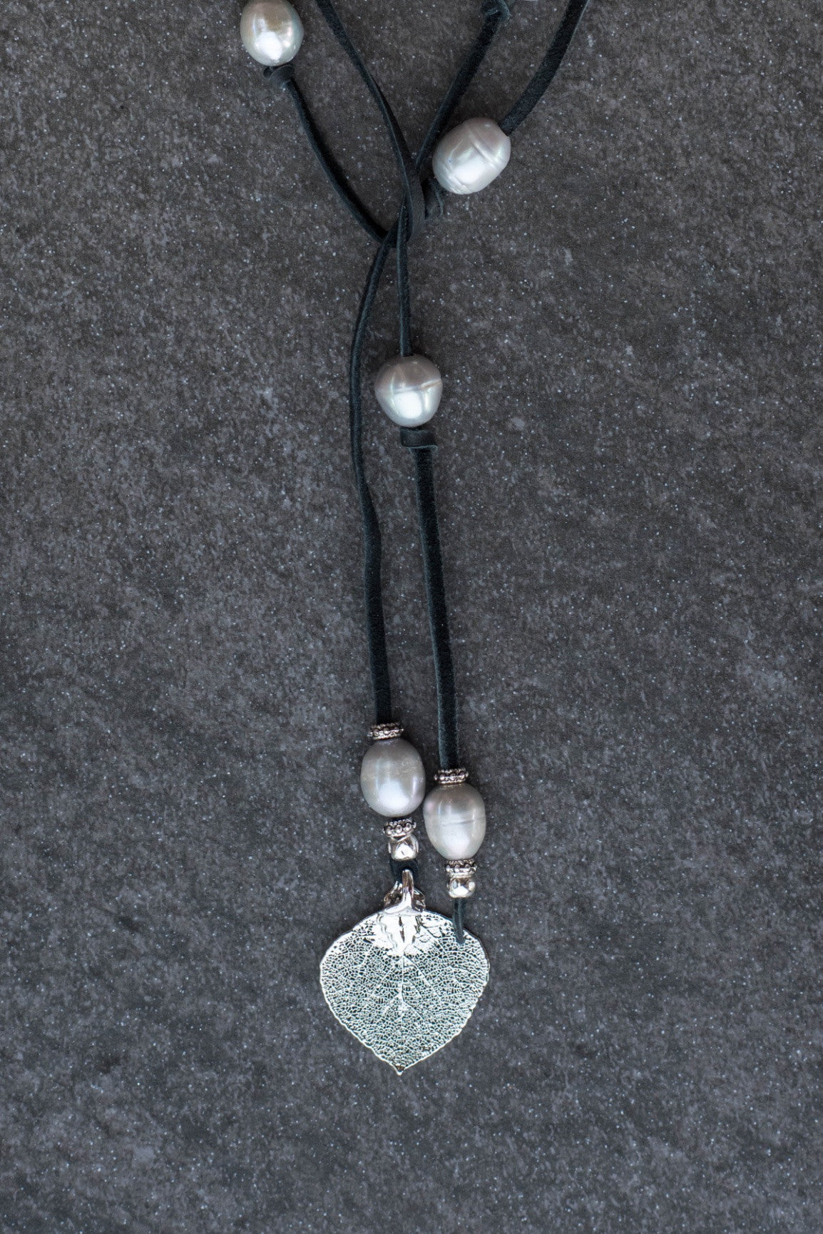 Lariat: Eight pearls highlight this versatile necklace, Silver freshwater pearls, silver Aspen leaf, black deerskin leather.