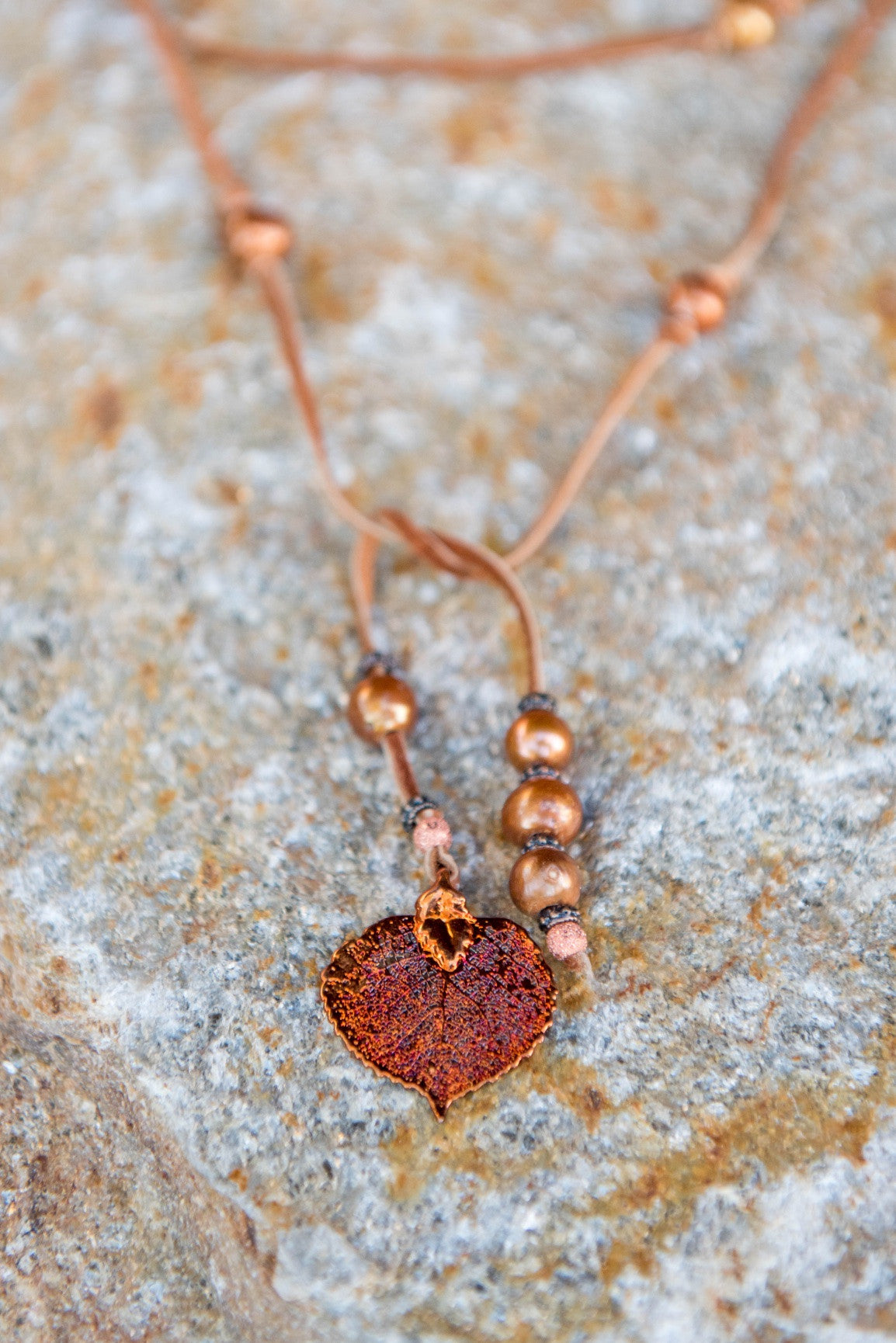 Lariat: twelve pearls highlight this versatile necklace, Bronze freshwater pearls, copper Aspen leaf, brown deerskin leather.