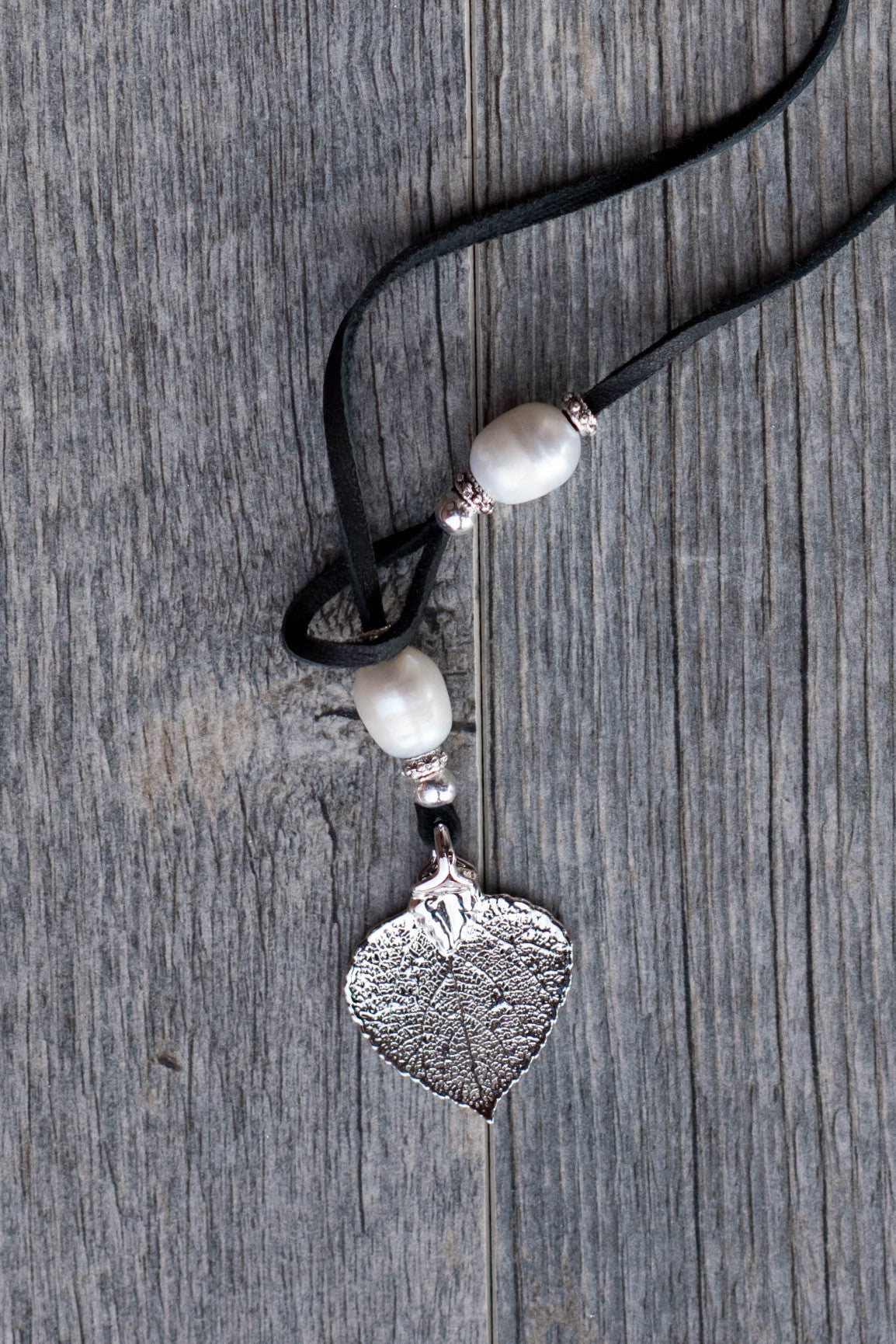 Three White pearls, silver leaf, black leather creates this original and trendy necklace