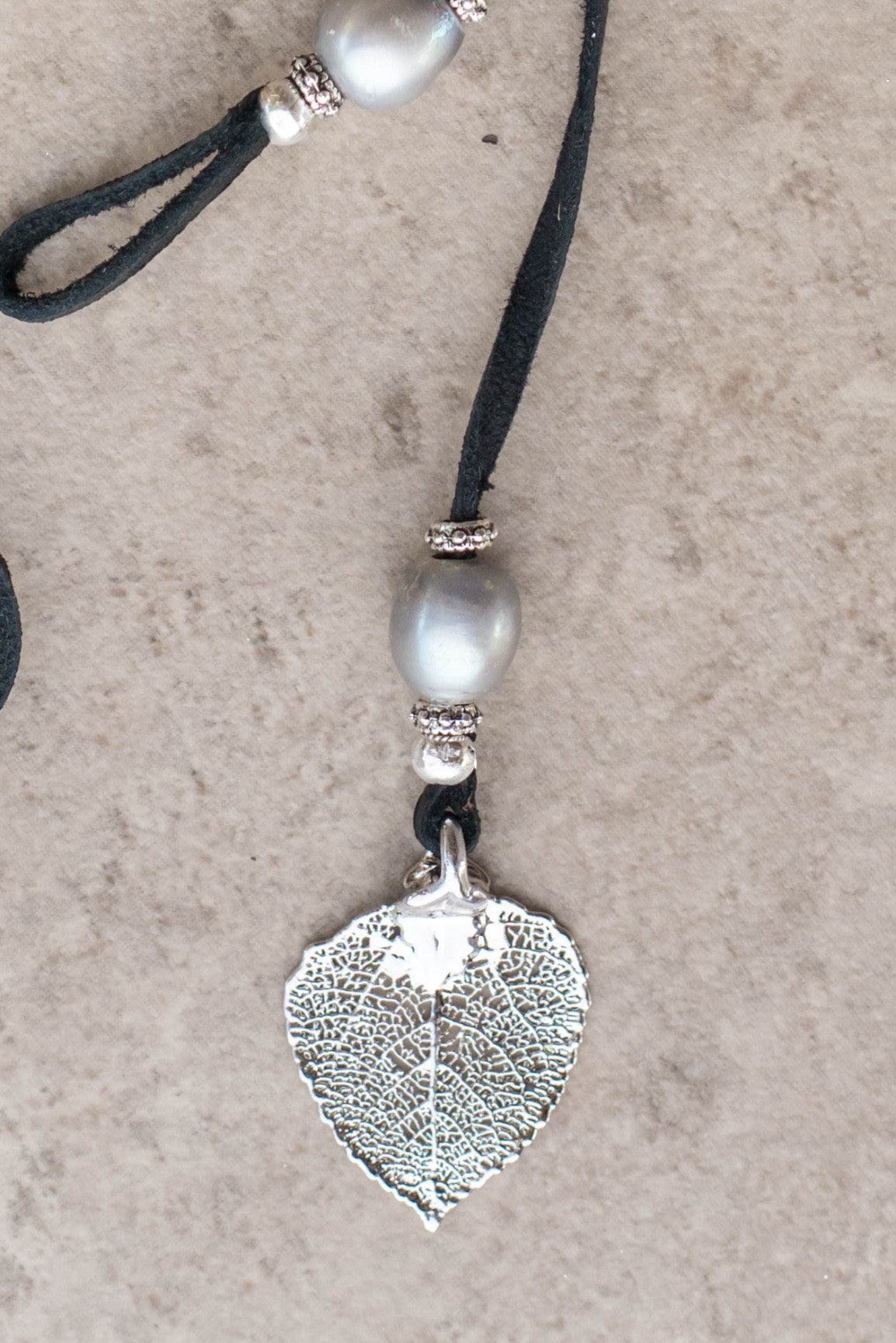 Three silver pearls, silver leaf, black leather creates this original and trendy necklace