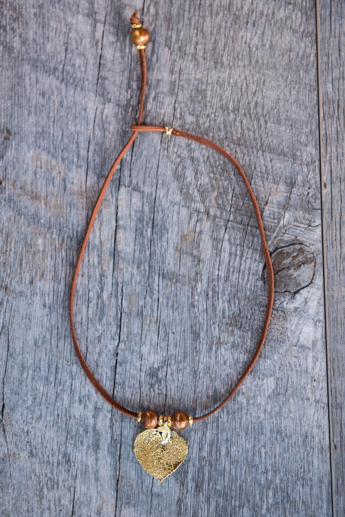 Three pearls choker: Bronze pearls with a gold leaf, come together with brown leather for this trendy versatile necklace