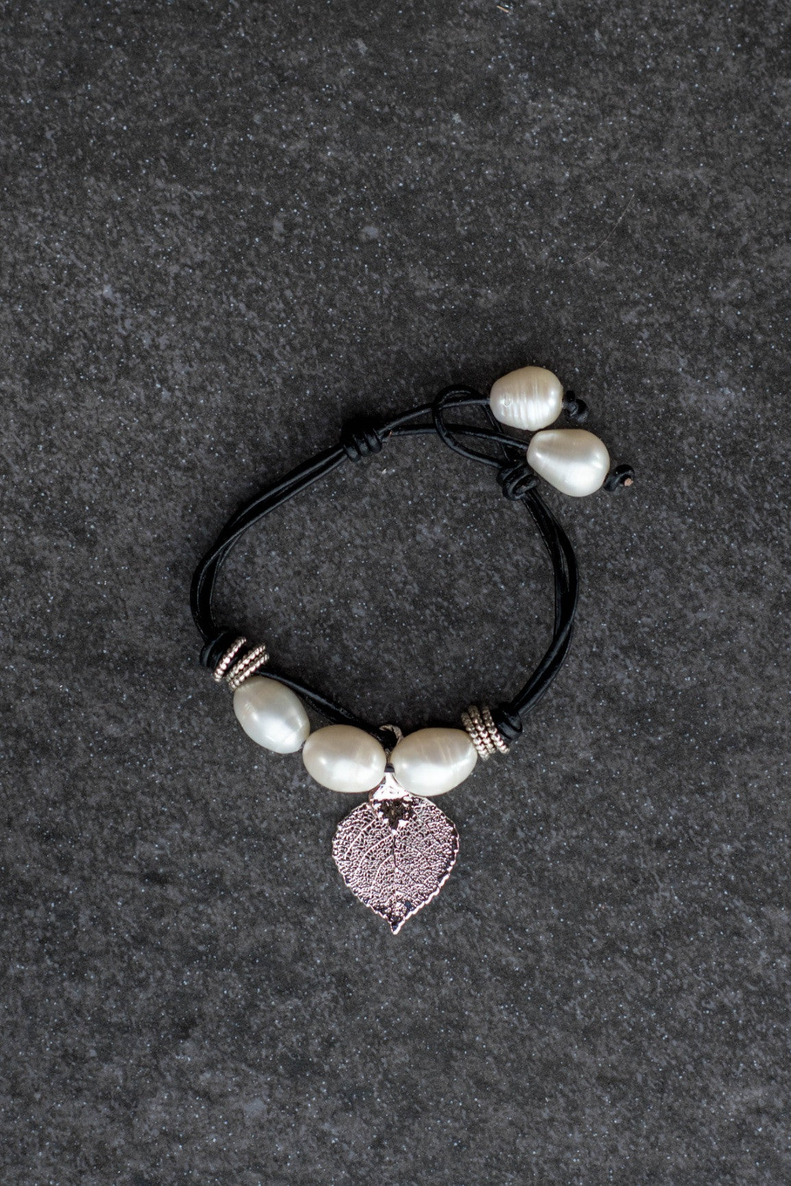 Five Pearls Bracelet: Three white pearls in front with a small silver leaf finished with two back white pearl, black leather cord.